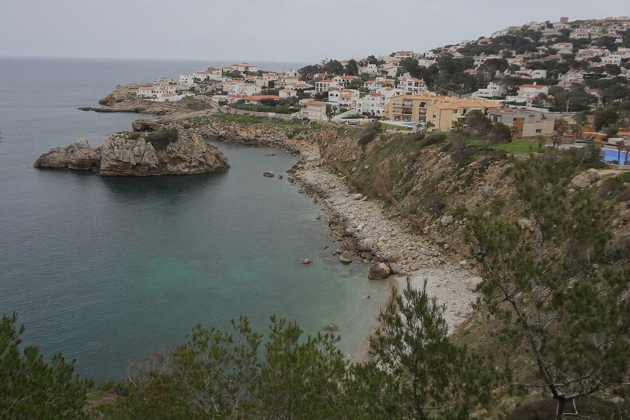 Rocky Illa Mateua cove and its offshore islet below a residential slope