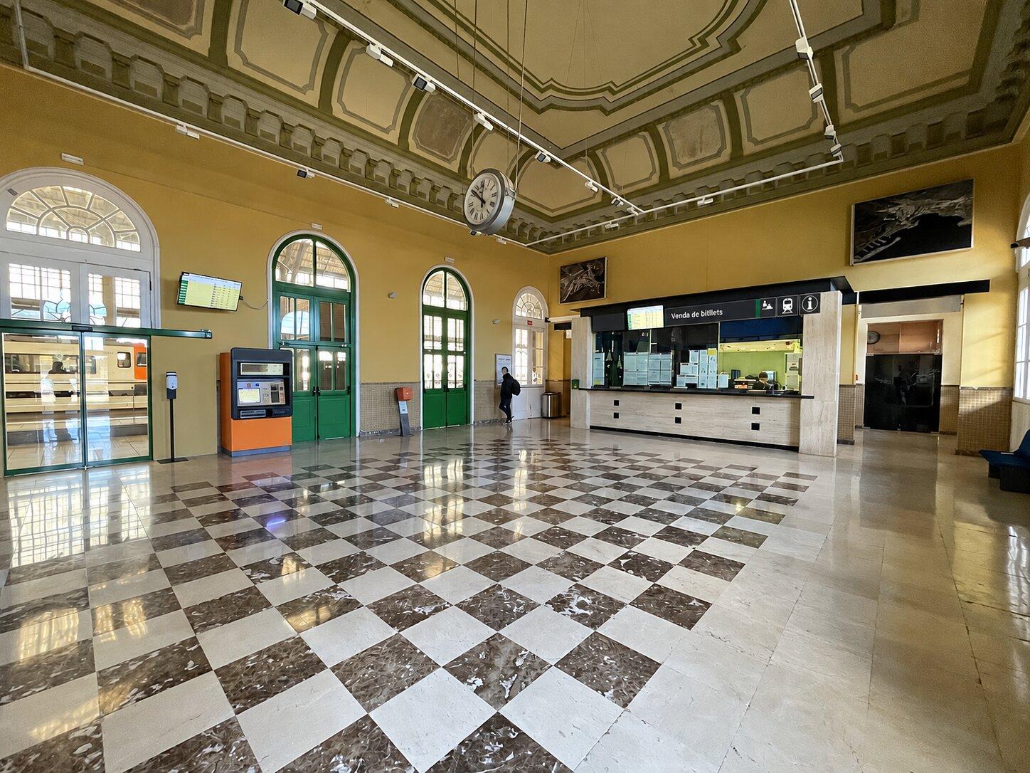 Ticket counters and a chequered floor inside Portbou railway station